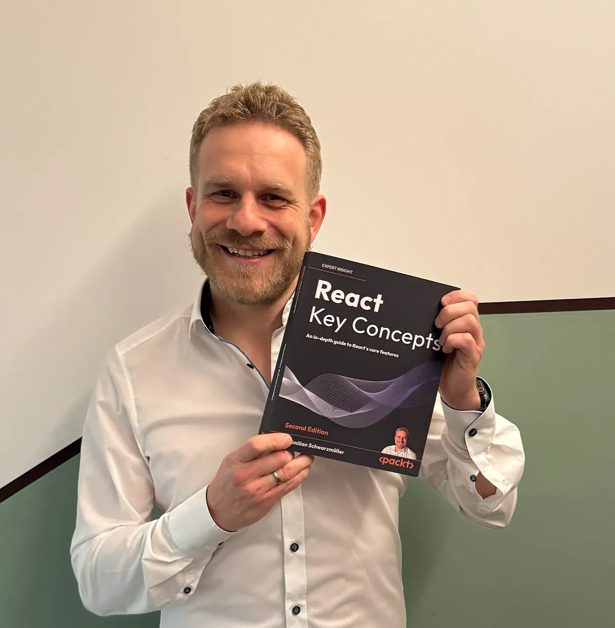 Max holding a phyiscal copy of his book 'React Key Concepts'